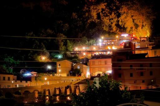 Veduta notturna di un paese con illuminazione calda, case e alberi sullo sfondo