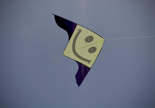 Aquilone con faccina sorridente, volo nel cielo blu